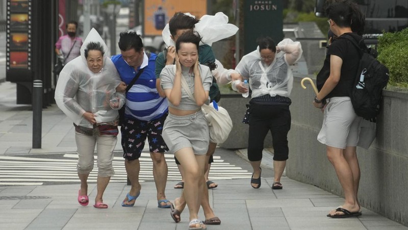 People struggle in the rain and wind as the tropical storm named Khanun approaches to the Korean Peninsular, in Busan, Thursday, Aug. 10, 2023. (AP Photo/Ahn Young-joon)