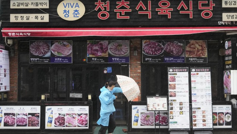 People struggle in the rain and wind as the tropical storm named Khanun approaches to the Korean Peninsular, in Busan, Thursday, Aug. 10, 2023. (AP Photo/Ahn Young-joon)