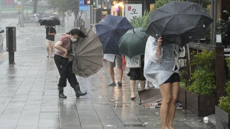 People struggle in the rain and wind as the tropical storm named Khanun approaches to the Korean Peninsular, in Busan, Thursday, Aug. 10, 2023. (AP Photo/Ahn Young-joon)