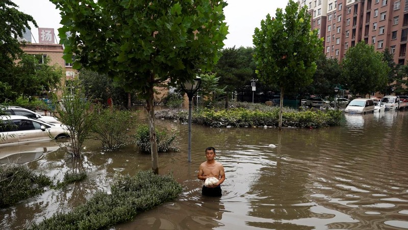 FILE PHOTO: FILE PHOTO:A man holding a child walks across a damaged bridge after the rains and floods brought by remnants of Typhoon Doksuri, in Zhuozhou, Hebei province, China August 7, 2023. REUTERS/Tingshu Wang     TPX IMAGES OF THE DAY/File Photo