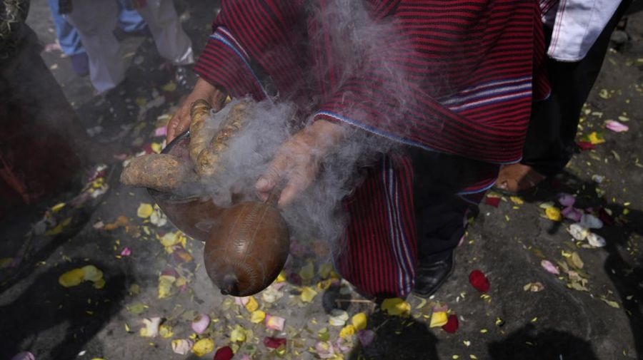 A shaman holds sweet potatoes and an instrument during a shamanic ritual calling for the earth's protection from contamination, one day before Earth World Day on San Cristobal hill in Lima, Peru, Friday, April 21, 2023. (AP Photo/MartÌn MejÌa)