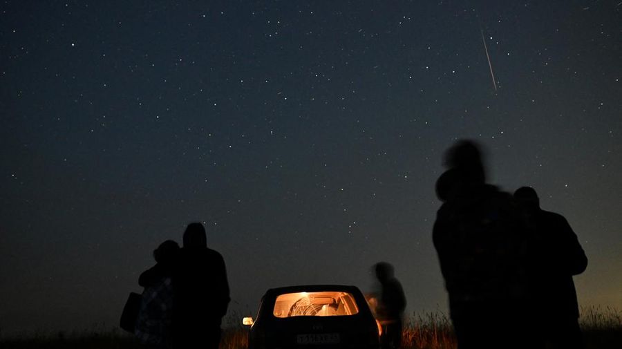 Orang-orang menyaksikan meteor melesat di langit malam selama hujan meteor Perseid tahunan di kota Siberia Yeniseysk di Wilayah Krasnoyarsk, Rusia 12 Agustus 2023. (REUTERS/Alexey Malgavko)