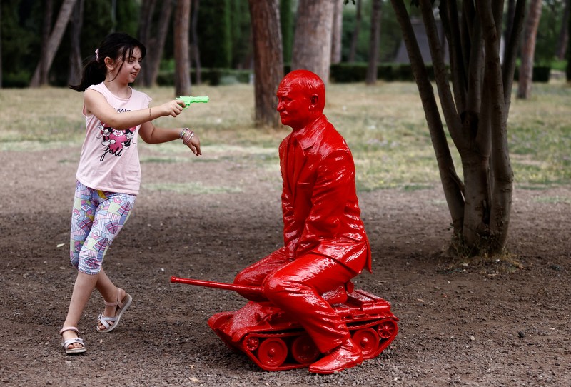 Anak-anak menyentuh patung Presiden Rusia Vladimir Putin seukuran manusia mengendarai tank kecil yang dibuat oleh seniman Prancis James Colomina di Villa Borghese di Roma, Italia, 3 Agustus 2023. (REUTERS/Yara Nardi)
