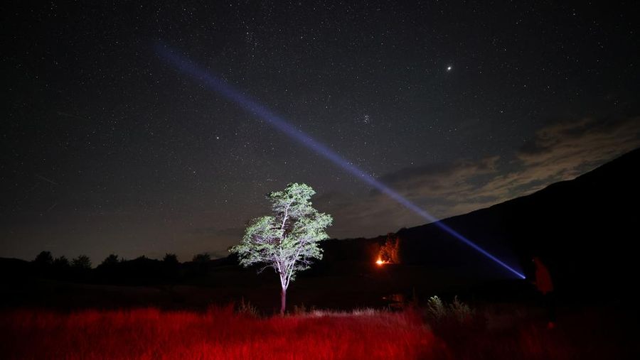 Seorang pria menggunakan sinar laser ke arah langit selama hujan meteor tahunan Perseid di Taman Nasional Shebenik, di Fushe Stude, Albania, 13 Agustus 2023. (REUTERS/Florion Goga)
