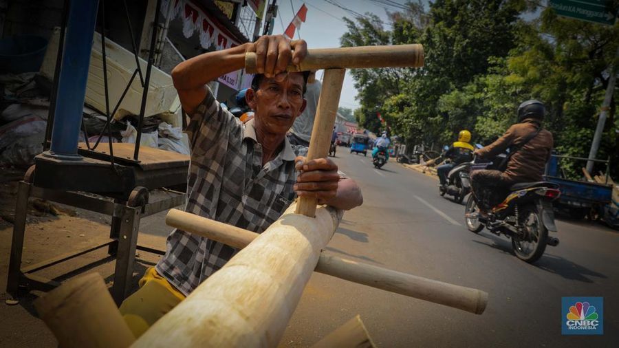 Pengrajin menyelesaikan pembuatan batang pinang untuk perlombaan HUT RI, Manggarai, Jakarta, Senin (14/8/2023). (CNBC Indonesia/Faisal Rahman)