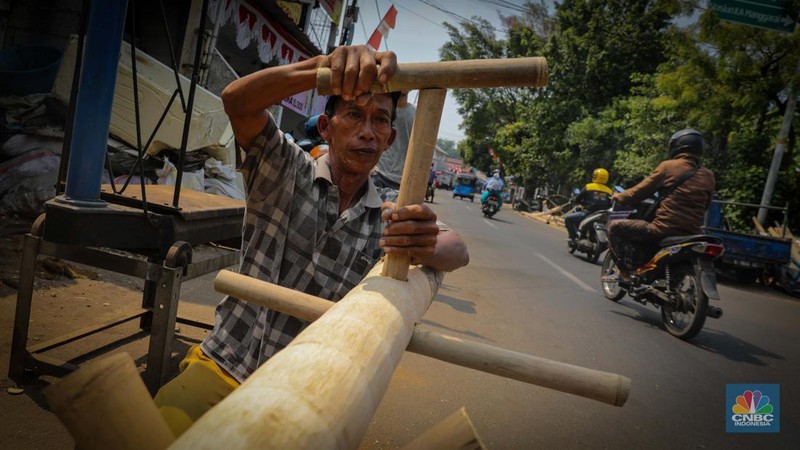 Pengrajin menyelesaikan pembuatan batang pinang untuk perlombaan HUT RI, Manggarai, Jakarta, Senin (14/8/2023). (CNBC Indonesia/Faisal Rahman)