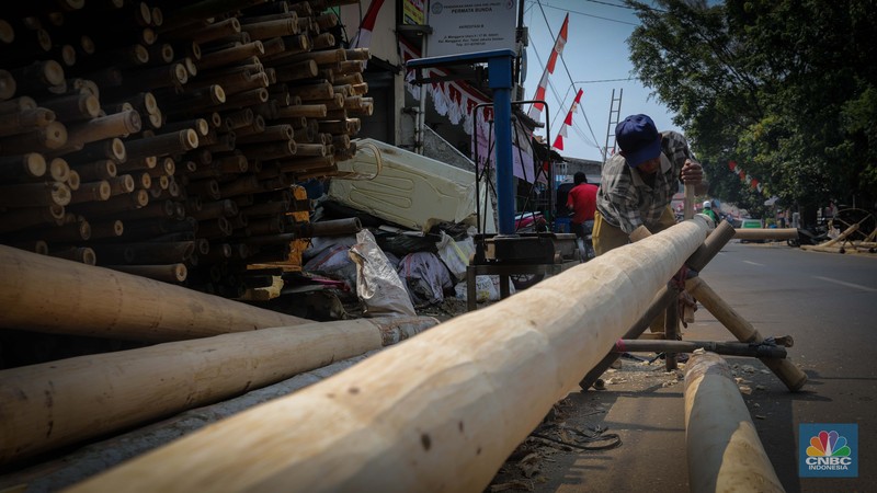 Pengrajin menyelesaikan pembuatan batang pinang untuk perlombaan HUT RI, Manggarai, Jakarta, Senin (14/8/2023). (CNBC Indonesia/Faisal Rahman)