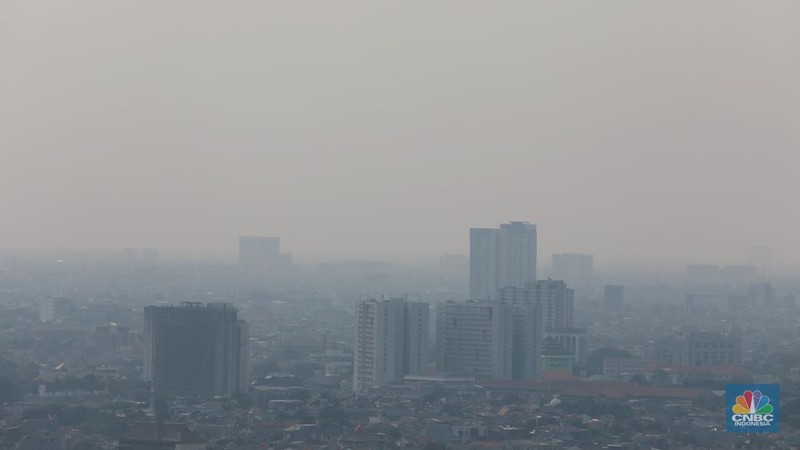 Sejumlah karyawan melihat gedung bertingkat yang tertutup oleh kabut polusi di Jakarta, Senin, (14/8). (CNBC Indonesia/Muhammad Sabki)