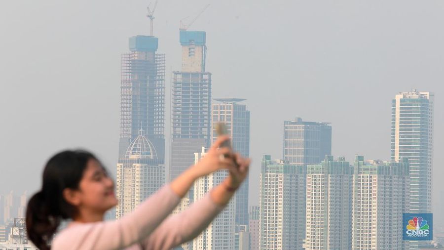 Sejumlah karyawan melihat gedung bertingkat yang tertutup oleh kabut polusi di Jakarta, Senin, (14/8). (CNBC Indonesia/Muhammad Sabki)