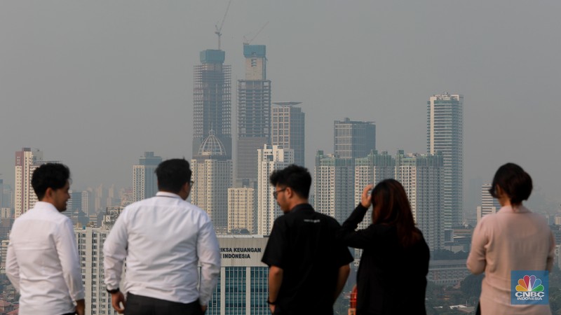 Sejumlah karyawan melihat gedung bertingkat yang tertutup oleh kabut polusi di Jakarta, Senin, (14/8). Sejumlah karyawan melihat gedung bertingkat yang tertutup oleh kabut polusi di Jakarta, Senin, (14/8). (CNBC Indonesia/Muhammad Sabki)
