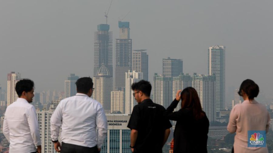 Sejumlah karyawan melihat gedung bertingkat yang tertutup oleh kabut polusi di Jakarta, Senin, (14/8). (CNBC Indonesia/Muhammad Sabki)