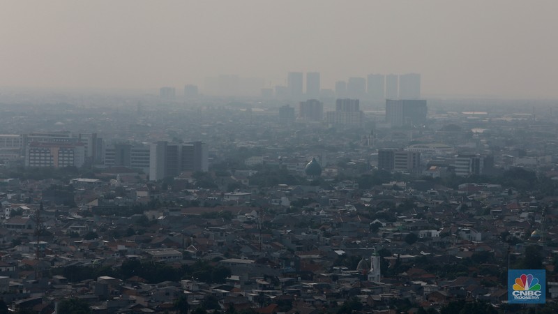 Sejumlah karyawan melihat gedung bertingkat yang tertutup oleh kabut polusi di Jakarta, Senin, (14/8). (CNBC Indonesia/Muhammad Sabki)