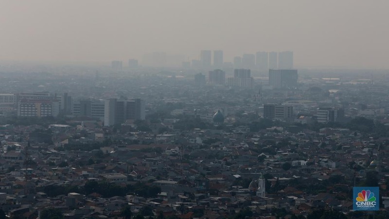 Sejumlah karyawan melihat gedung bertingkat yang tertutup oleh kabut polusi di Jakarta, Senin, (14/8). (CNBC Indonesia/Muhammad Sabki)
