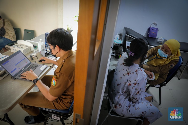 Dokter melakukan pemeriksaan kesehatan terhadap pasien bergejala Infeksi Saluran Pernapasan Akut (ISPA) di Puskesmas Kecamatan Mampang Prapatan, Jakarta Selatan, Selasa (15/8/2023). Tingginya angka polusi udara di Jakarta belakangan ini menyebabkan jumlah warga yang terinfeksi penyakit ISPA meningkat. (CNBC Indonesia/Faisal Rahman)