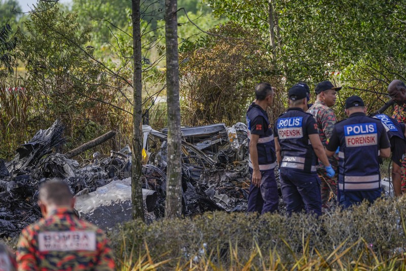 Seorang anggota departemen pemadam kebakaran dan penyelamatan memeriksa lokasi jatuhnya pesawat kecil di distrik Shah Alam, Malaysia, Kamis, 17 Agustus 2023. Polisi mengatakan sebuah pesawat kecil jatuh di pinggiran negara bagian Selangor tengah Malaysia, dengan banyak jenazah pulih. (AP Photo/Vincent Thian)