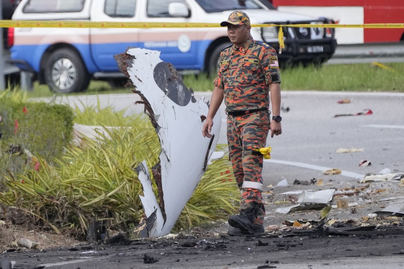 Seorang anggota departemen pemadam kebakaran dan penyelamatan memeriksa lokasi jatuhnya pesawat kecil di distrik Shah Alam, Malaysia, Kamis, 17 Agustus 2023. Polisi mengatakan sebuah pesawat kecil jatuh di pinggiran negara bagian Selangor tengah Malaysia, dengan banyak jenazah pulih. (AP Photo/Vincent Thian)
