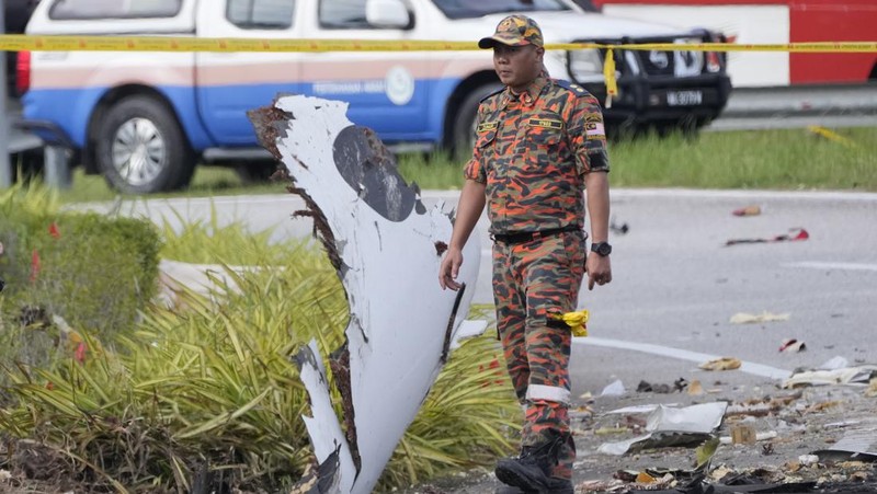 Seorang anggota departemen pemadam kebakaran dan penyelamatan memeriksa lokasi jatuhnya pesawat kecil di distrik Shah Alam, Malaysia, Kamis, 17 Agustus 2023. Polisi mengatakan sebuah pesawat kecil jatuh di pinggiran negara bagian Selangor tengah Malaysia, dengan banyak jenazah pulih. (AP Photo/Vincent Thian)