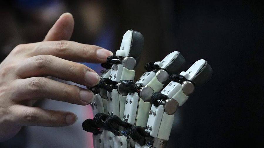 Seorang pengunjung menyentuh jari robot selama Konferensi Robot Dunia tahunan di Pusat Pameran dan Konvensi Internasional Etrong di pinggiran Beijing, Kamis, 17 Agustus 2023. (AP Photo/Andy Wong)