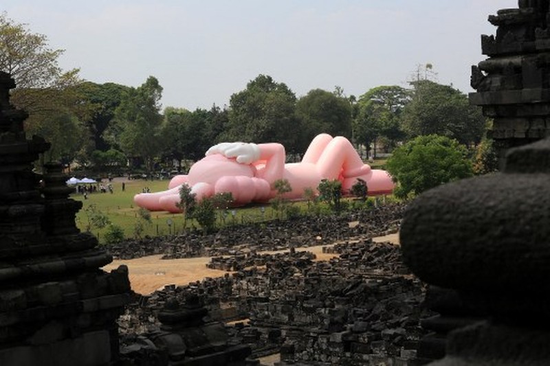 Instalasi seni berukuran raksasa yang dikenal sebagai KAWS, karya seniman Amerika Brian Donnelly terlihat menghiasi Candi Prambanan, Yogyakarta, Jawa Tengah. (DEVI RAHMAN / AFP) Instalasi seni berukuran raksasa yang dikenal sebagai KAWS, karya seniman Amerika Brian Donnelly terlihat menghiasi Candi Prambanan, Yogyakarta, Jawa Tengah. (DEVI RAHMAN / AFP)
