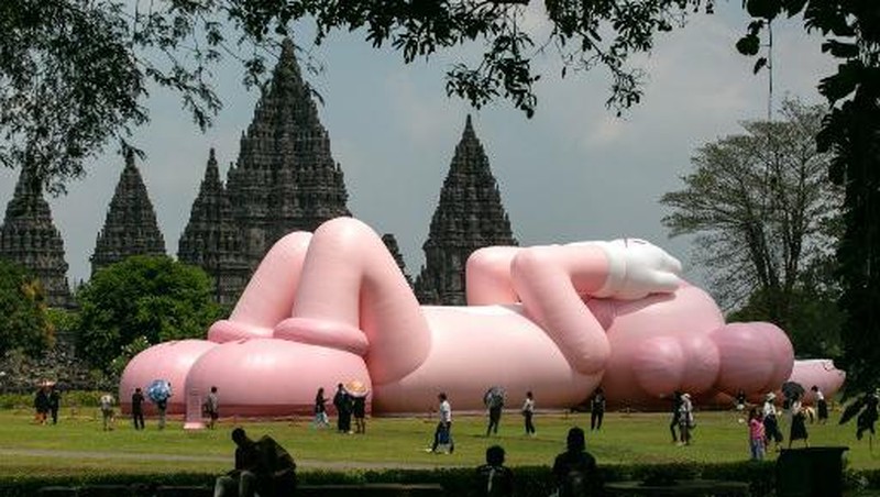 Instalasi seni berukuran raksasa yang dikenal sebagai KAWS, karya seniman Amerika Brian Donnelly terlihat menghiasi Candi Prambanan, Yogyakarta, Jawa Tengah. (DEVI RAHMAN / AFP)