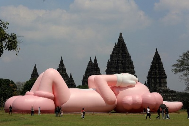 Instalasi seni berukuran raksasa yang dikenal sebagai KAWS, karya seniman Amerika Brian Donnelly terlihat menghiasi Candi Prambanan, Yogyakarta, Jawa Tengah. (DEVI RAHMAN / AFP)
