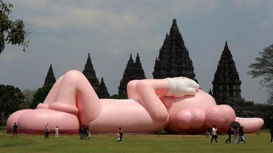 Instalasi seni berukuran raksasa yang dikenal sebagai KAWS, karya seniman Amerika Brian Donnelly terlihat menghiasi Candi Prambanan, Yogyakarta, Jawa Tengah. (DEVI RAHMAN / AFP)