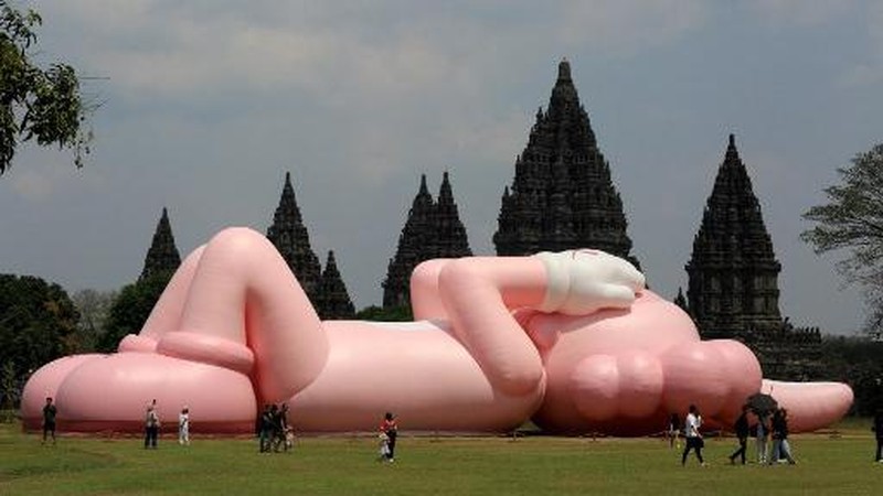 Instalasi seni berukuran raksasa yang dikenal sebagai KAWS, karya seniman Amerika Brian Donnelly terlihat menghiasi Candi Prambanan, Yogyakarta, Jawa Tengah. (DEVI RAHMAN / AFP)