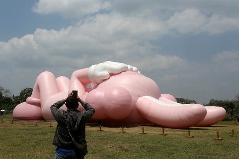 Instalasi seni berukuran raksasa yang dikenal sebagai KAWS, karya seniman Amerika Brian Donnelly terlihat menghiasi Candi Prambanan, Yogyakarta, Jawa Tengah. (DEVI RAHMAN / AFP) Instalasi seni berukuran raksasa yang dikenal sebagai KAWS, karya seniman Amerika Brian Donnelly terlihat menghiasi Candi Prambanan, Yogyakarta, Jawa Tengah. (DEVI RAHMAN / AFP)