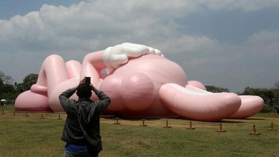 Instalasi seni berukuran raksasa yang dikenal sebagai KAWS, karya seniman Amerika Brian Donnelly terlihat menghiasi Candi Prambanan, Yogyakarta, Jawa Tengah. (DEVI RAHMAN / AFP)