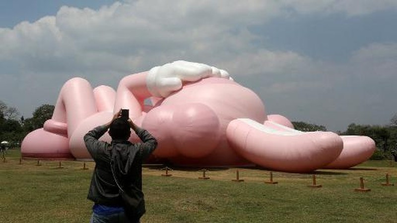 Instalasi seni berukuran raksasa yang dikenal sebagai KAWS, karya seniman Amerika Brian Donnelly terlihat menghiasi Candi Prambanan, Yogyakarta, Jawa Tengah. (DEVI RAHMAN / AFP)