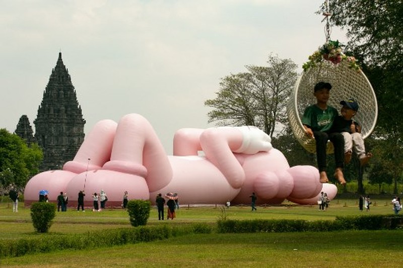 Instalasi seni berukuran raksasa yang dikenal sebagai KAWS, karya seniman Amerika Brian Donnelly terlihat menghiasi Candi Prambanan, Yogyakarta, Jawa Tengah. (DEVI RAHMAN / AFP) Instalasi seni berukuran raksasa yang dikenal sebagai KAWS, karya seniman Amerika Brian Donnelly terlihat menghiasi Candi Prambanan, Yogyakarta, Jawa Tengah. (DEVI RAHMAN / AFP)