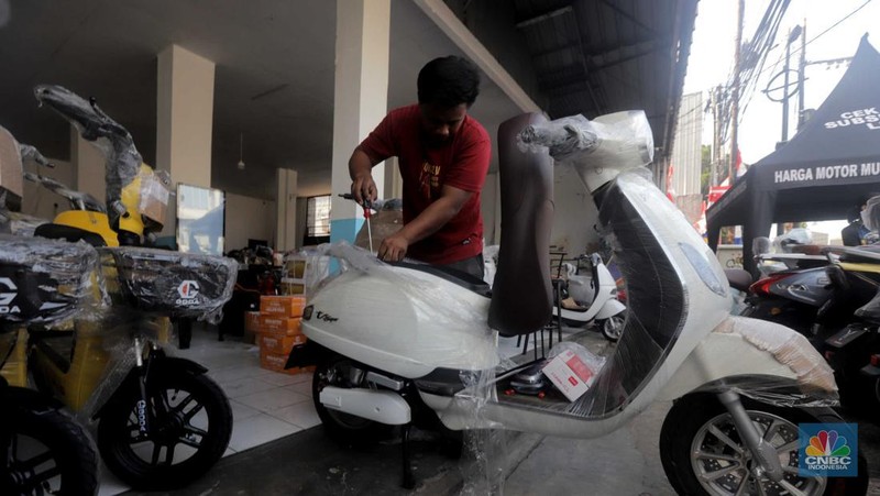 Pekerja merapikan kendaraan motor listrik di salah satu dealer motor listrik, Jakarta, Senin (21/8/2023). (CNBC Indonesia/Muhammad Sabki)