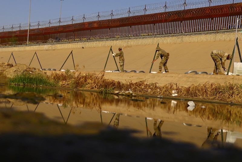 Garda Nasional Texas melakukan pemasangan pagar kawat berduri di tepi sungai Rio Bravo yang merupakan perbatasan antara Amerika Serikat (AS) dan Meksiko pada Selasa (22/8/2023). (REUTERS/Jose Luis Gonzalez)
