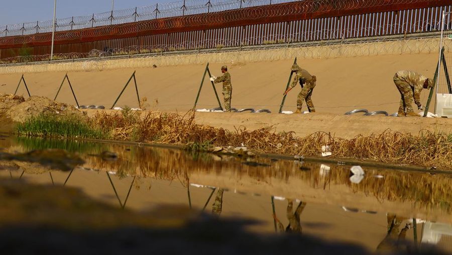 Garda Nasional Texas melakukan pemasangan pagar kawat berduri di tepi sungai Rio Bravo yang merupakan perbatasan antara Amerika Serikat (AS) dan Meksiko pada Selasa (22/8/2023). (REUTERS/Jose Luis Gonzalez)