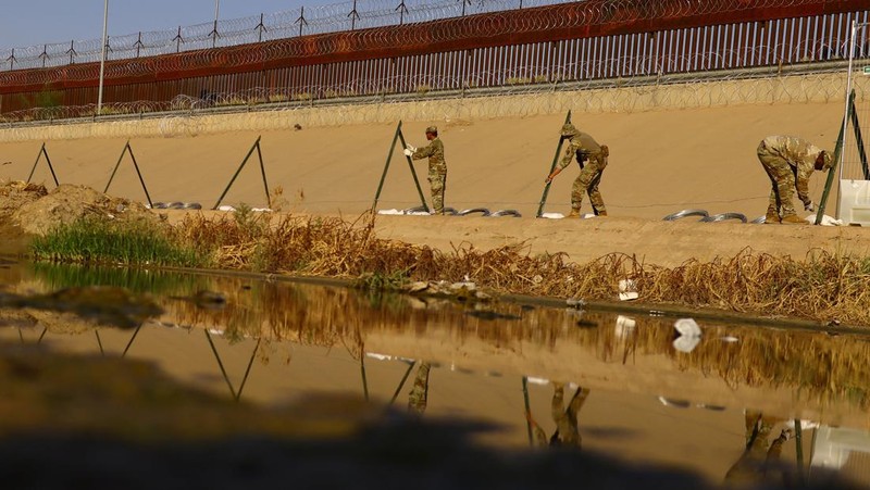 Garda Nasional Texas melakukan pemasangan pagar kawat berduri di tepi sungai Rio Bravo yang merupakan perbatasan antara Amerika Serikat (AS) dan Meksiko pada Selasa (22/8/2023). (REUTERS/Jose Luis Gonzalez)