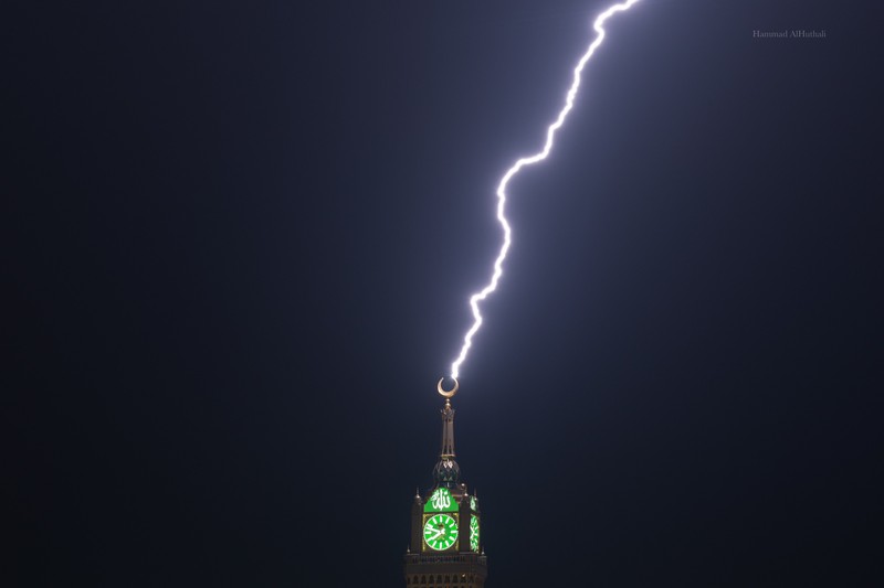 Sebuah gambar yang diambil pada 22 Agustus 2023 menunjukkan petir di atas menara jam Mekkah di Arab Saudi. Badai dahsyat menutup sekolah-sekolah pada tanggal 23 Agustus di wilayah Mekah di kerajaan gurun pasir, tempat Masjidil Haram berada, yang dilanda hujan lebat dan angin semalaman, kata para saksi mata. (Hammad Al-Huthali / AFP)