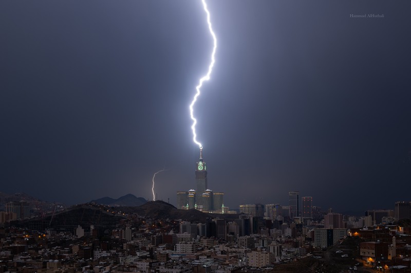 Sebuah gambar yang diambil pada 22 Agustus 2023 menunjukkan petir di atas menara jam Mekkah di Arab Saudi. Badai dahsyat menutup sekolah-sekolah pada tanggal 23 Agustus di wilayah Mekah di kerajaan gurun pasir, tempat Masjidil Haram berada, yang dilanda hujan lebat dan angin semalaman, kata para saksi mata. (Hammad Al-Huthali / AFP)