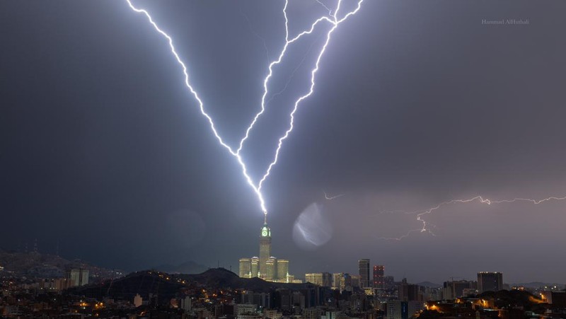 Sebuah gambar yang diambil pada 22 Agustus 2023 menunjukkan petir di atas menara jam Mekkah di Arab Saudi. Badai dahsyat menutup sekolah-sekolah pada tanggal 23 Agustus di wilayah Mekah di kerajaan gurun pasir, tempat Masjidil Haram berada, yang dilanda hujan lebat dan angin semalaman, kata para saksi mata. (Hammad Al-Huthali / AFP)