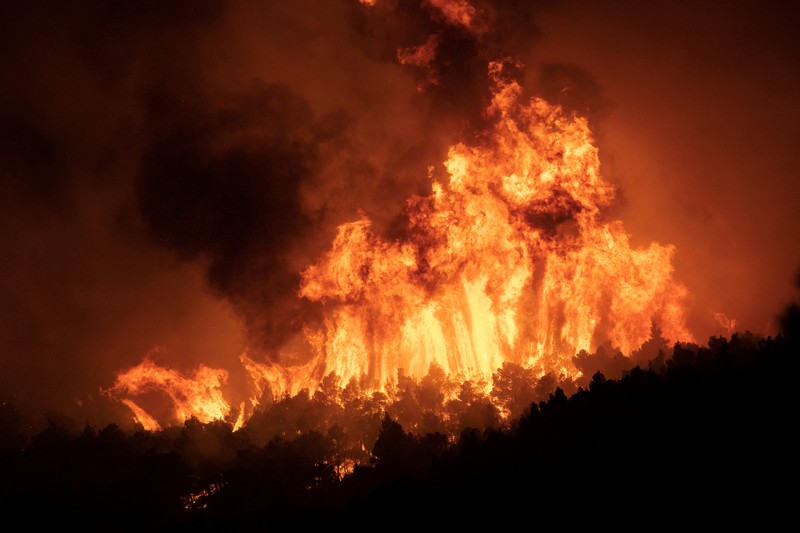 Petugas pemadam kebakaran melihat api yang berkobar di Gunung Parnitha, di Athena, Yunani, 24 Agustus 2023. (REUTERS/Nicolas Economou)