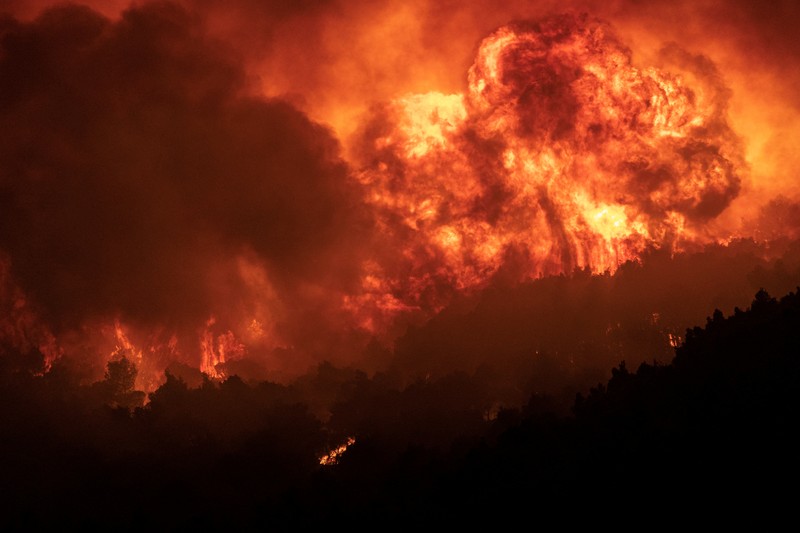 Petugas pemadam kebakaran melihat api yang berkobar di Gunung Parnitha, di Athena, Yunani, 24 Agustus 2023. (REUTERS/Nicolas Economou)