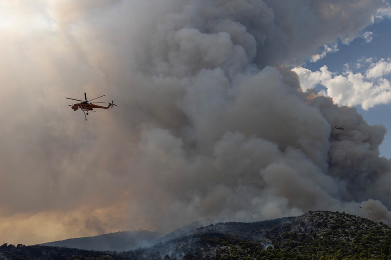 Petugas pemadam kebakaran melihat api yang berkobar di Gunung Parnitha, di Athena, Yunani, 24 Agustus 2023. (REUTERS/Nicolas Economou)