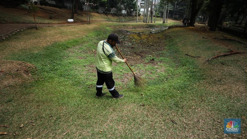 Seorang pekerja membersihkan kolam yang kering di kawasan Taman Meruya Ilir Jakarta, Senin (28/8/2023). Musim kemarau yang berkepanjangan mengakibatkan kolam-kolam di taman Jakarta mengalami kekeringan. (CNBC Indonesia/Tri Susilo)
