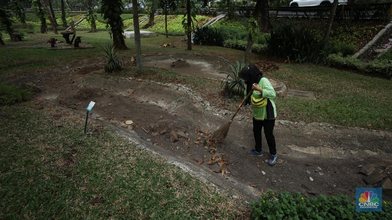 Seorang pekerja membersihkan kolam yang kering di kawasan Taman Meruya Ilir Jakarta, Senin (28/8/2023). Musim kemarau yang berkepanjangan mengakibatkan kolam-kolam di taman Jakarta mengalami kekeringan. (CNBC Indonesia/Tri Susilo)