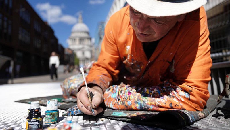 Ben Wilson, seniman, melukis di Millennium Bridge, London, Inggris, 21 Agustus 2023. (REUTERS/Anna Gordon)