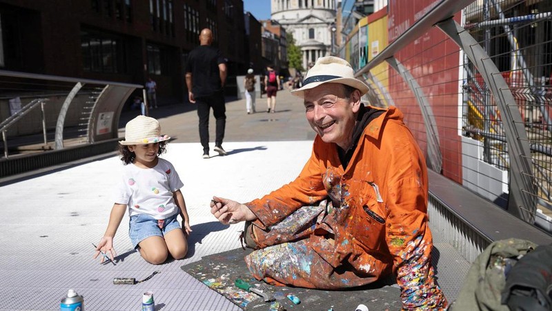 Ben Wilson, seniman, melukis di Millennium Bridge, London, Inggris, 21 Agustus 2023. (REUTERS/Anna Gordon)