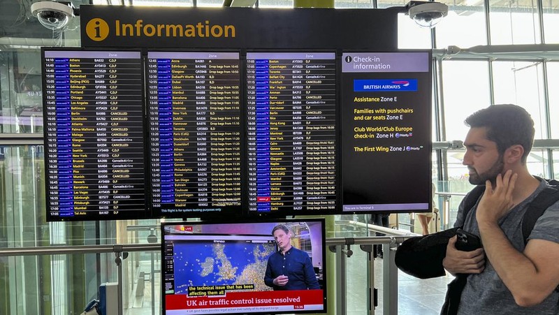 Seorang anggota staf British Airways berbicara kepada penumpang di Bandara Heathrow, ketika Layanan Lalu Lintas Udara Nasional Inggris (NATS) membatasi lalu lintas udara Inggris karena masalah teknis yang menyebabkan penundaan, di London, Inggris, 28 Agustus 2023. (REUTERS/Hollie Adams)