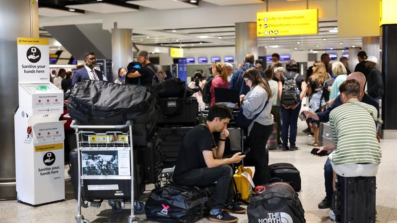 Seorang anggota staf British Airways berbicara kepada penumpang di Bandara Heathrow, ketika Layanan Lalu Lintas Udara Nasional Inggris (NATS) membatasi lalu lintas udara Inggris karena masalah teknis yang menyebabkan penundaan, di London, Inggris, 28 Agustus 2023. (REUTERS/Hollie Adams)