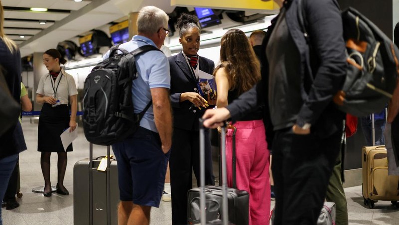 Seorang anggota staf British Airways berbicara kepada penumpang di Bandara Heathrow, ketika Layanan Lalu Lintas Udara Nasional Inggris (NATS) membatasi lalu lintas udara Inggris karena masalah teknis yang menyebabkan penundaan, di London, Inggris, 28 Agustus 2023. (REUTERS/Hollie Adams)