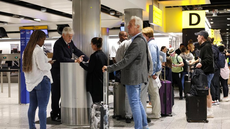 Seorang anggota staf British Airways berbicara kepada penumpang di Bandara Heathrow, ketika Layanan Lalu Lintas Udara Nasional Inggris (NATS) membatasi lalu lintas udara Inggris karena masalah teknis yang menyebabkan penundaan, di London, Inggris, 28 Agustus 2023. (REUTERS/Hollie Adams)
