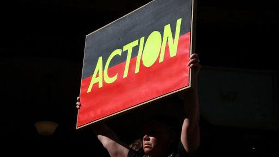 An Australian Aboriginal activist holds a placard as she participates in a rally in support of climate activist Deanna 